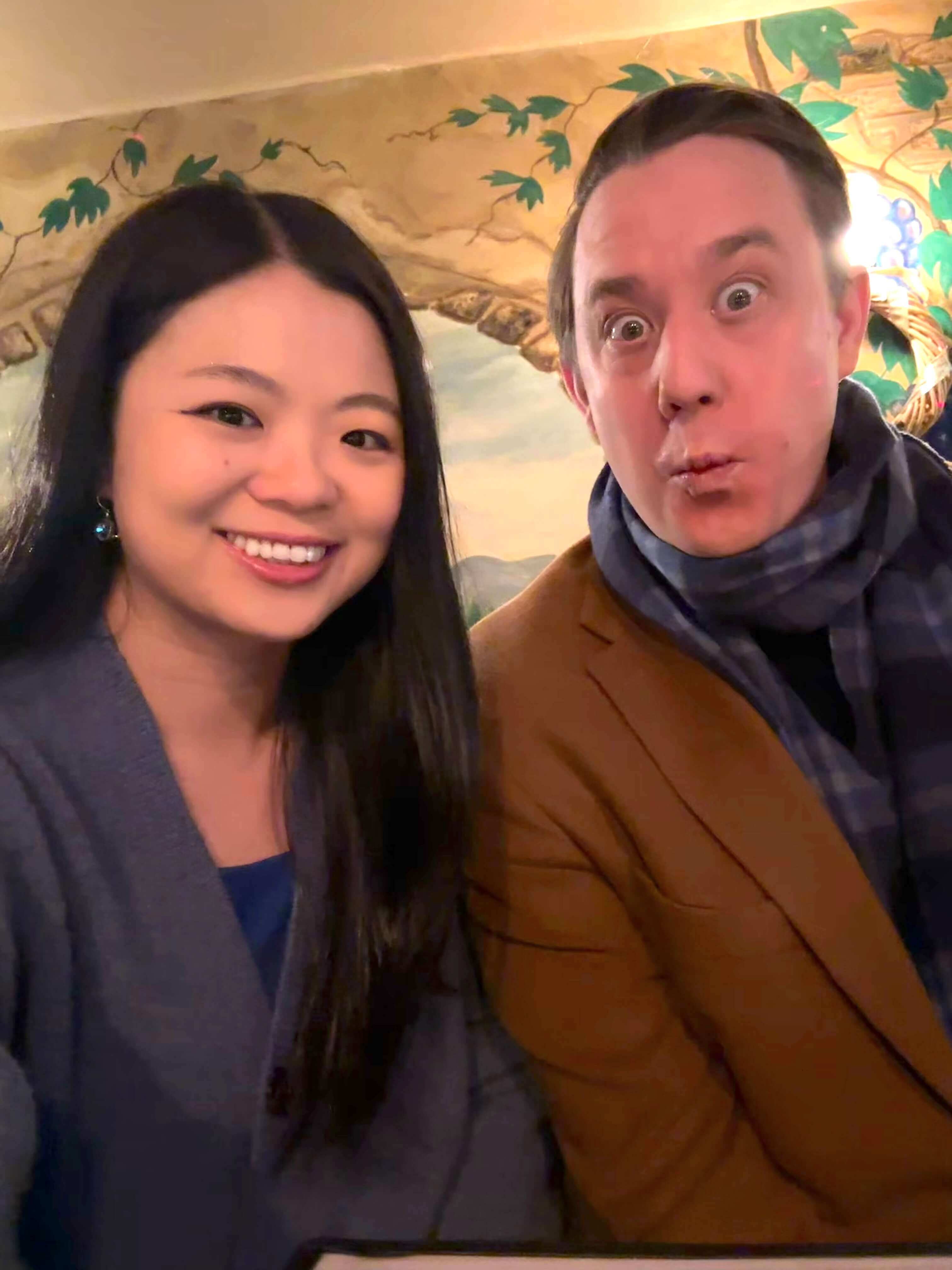 Two co-founders sitting side by side indoors, smiling at the camera in a casual, relaxed setting.