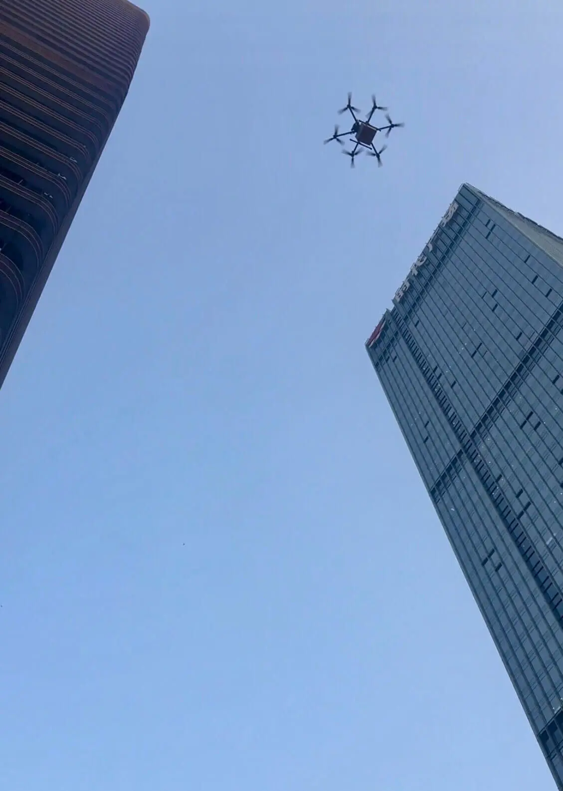 A woman smiling outdoors in Shenzhen with trees in the background, shown as a video cover image with the title “We Tested China’s Drone Delivery” displayed across the center, introducing a story about testing drone food delivery in China.